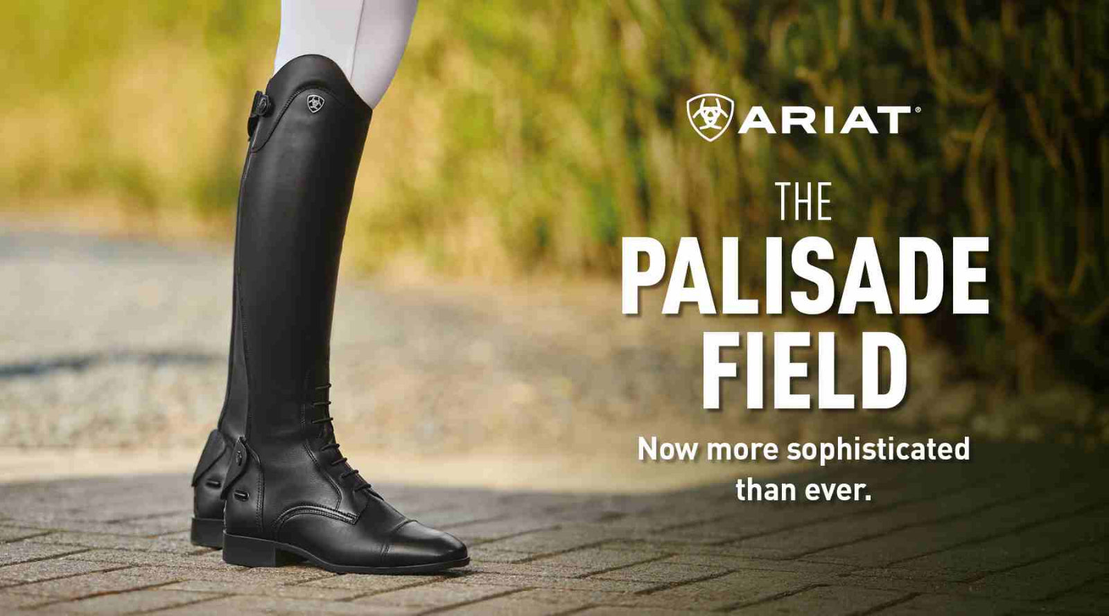 Black riding boots with Ariat branding on a blurred outdoor background
